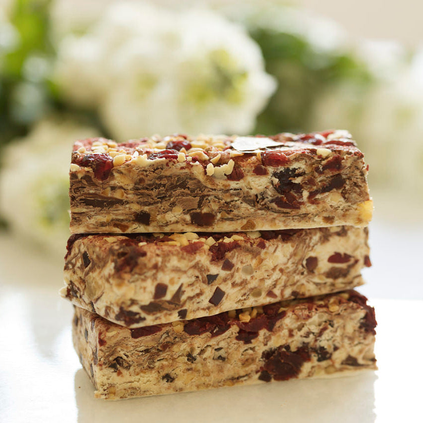 Stack of Nougat bars on a white surface with blurred flowers in the background